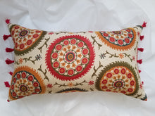 Load image into Gallery viewer, Boho-Retro inspired pillow cover lined with red tassels, main colour is cream with beautiful multi-coloured circles (burnt oranges, green, red, tangerine, and turquoise) lined with flowers and stems. 14 x 24 inches made from mixed fibers.
